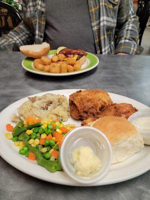 Broasted chicken with mashed potatoes, mixed vegetables,  and dinner roll.  Bacon Cheeseburger with tator tots.