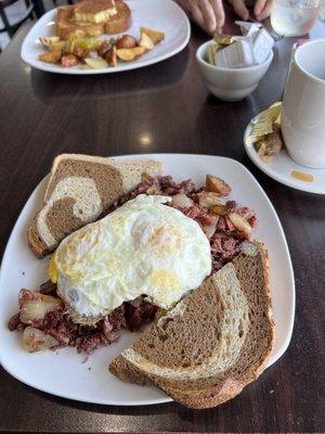 Corned beef hash topped with two perfectly cooked eggs with rye bread.