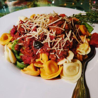 Rainbow tortellini topped with a bolognese sauce