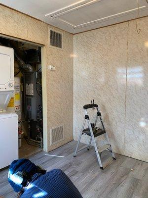 Before remodel - Stackable placed near original galvanized pipe drain and dryer outlet. New ceramic flooring replaced yellowing linoleum.