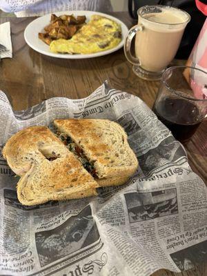 Light and Fit sandwich and black coffee in the foreground, omelet with potatoes and The Daily latte in the background