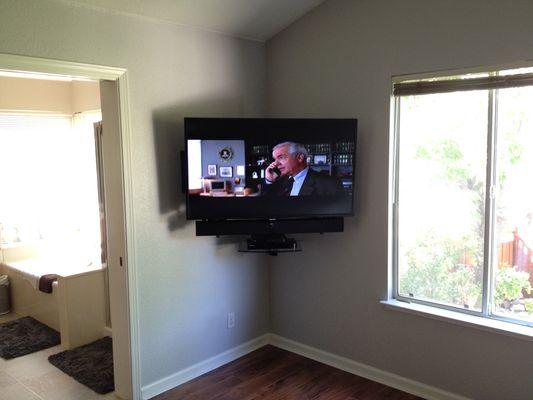 TV with attached soundbar, equipment located on corner shelf just under TV.