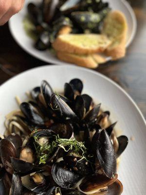 Mediterranean mussels with pasta underneath and other one is the pesto mussels with crispy garlic bread.