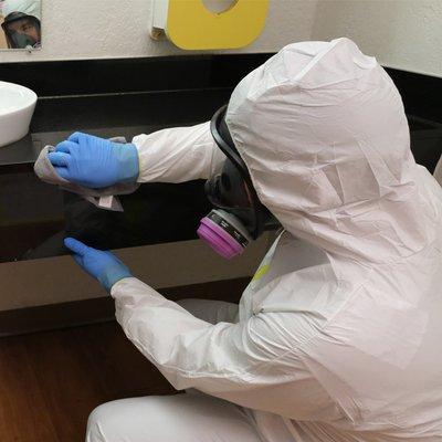 Biohazard technician cleaning stone vanity top.