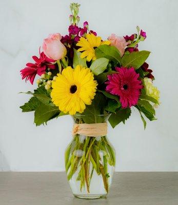 Eloise - Colorful bouquet of mixed flowers says "Spring is here!". The roses and gerbers are in a rose rose with raffia wrapped vase.