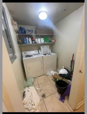 Broader photo of laundry room floor with the prior tenant's belongings and trash.