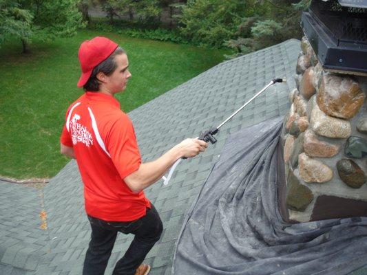 Applying a water repellant to the masonry chimney to prevent deterioration from weathering.