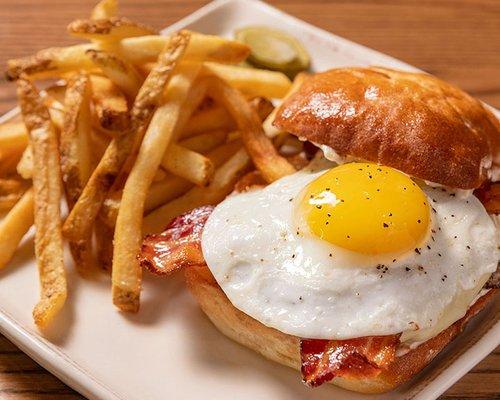 Farmhouse Burger with applewood smoked bacon, fried sunny egg, American cheese, and roasted garlic aioli on a potato bun.