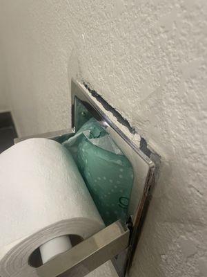 Toilet paper holder broken off wall and held on with clear tape