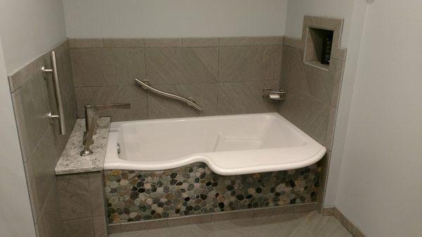 Transfer tub that allows client to sit on ledge and safely rotate torso into tub.  Wavy grab bars allow for a safe entrance and exit.