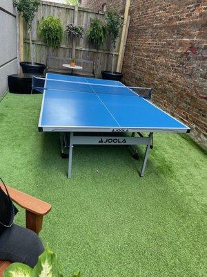 Hidden area of the back patio, featuring a ping pong table in the summertime.