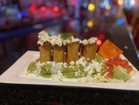 Delicious chicken flautas over a bed of guacamole.