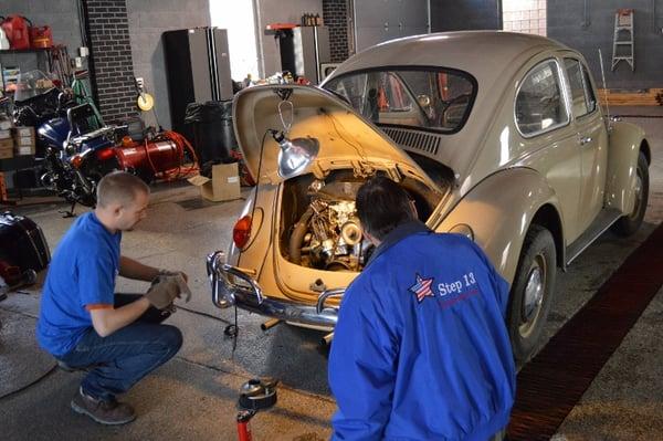 Step 13 men repairing a donated vehicle.