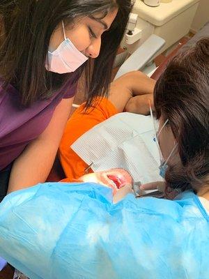 Dr. Zhang performs fillings for a patient with help of dental assistant Ana.