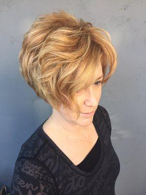 Short Asymmetrical haircut on curly hair. Color is a combination of soft copper and golden blondes, by Owner Ken Bradshaw.