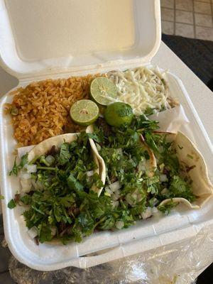 3 barbacoa tacos buried under lots of cilantro and onion with rice and beans.