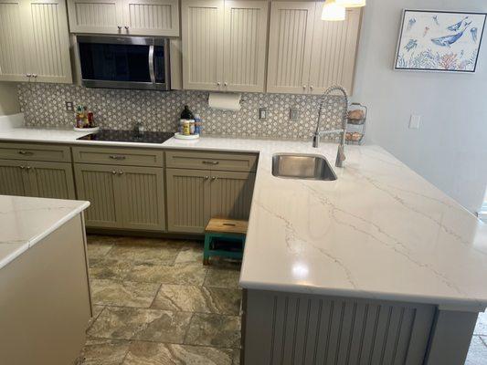 Completed kitchen with quartz counters, marble backsplash, new sink, faucet, cooktop.