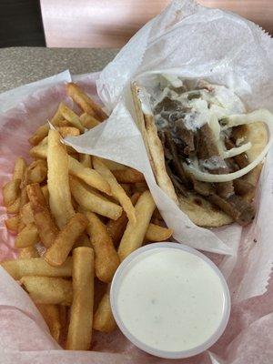 Gyro sandwich combo with a taziki sauce on the side.