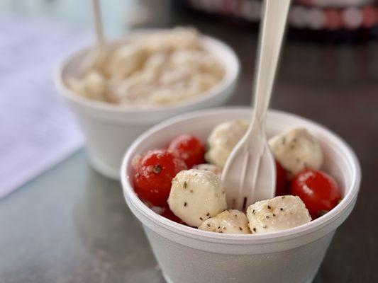 Tomato, basil, mozzarella salad and potato salad in the back