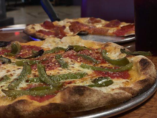 Personal pizza with green peppers on one and pepperoni on the other.