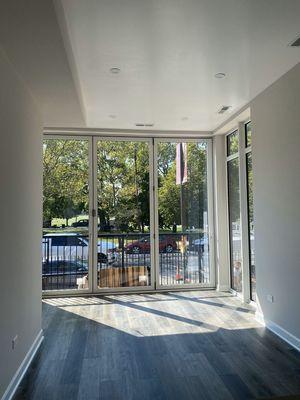 A large living and dining area flooded with natural light, featuring an oversized Juliette balcony with breathtaking views of Douglas Park.