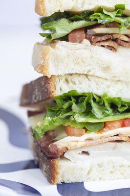 A classic turkey club: Turkey, bacon, Swiss, tomato, lettuce and mayonnaise on rustic white bread