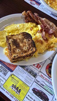 Scrambled eggs, bacon, raising toast and potatoes