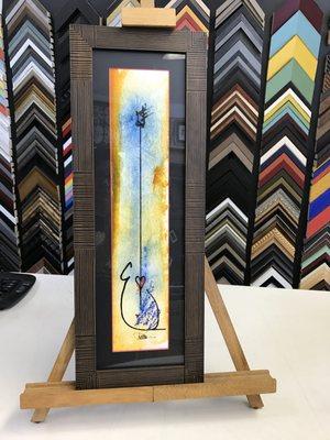 Original piece of art framed using a colored core mat & profile that reflects the neck of a guitar. Prefect for space between doors/windows.