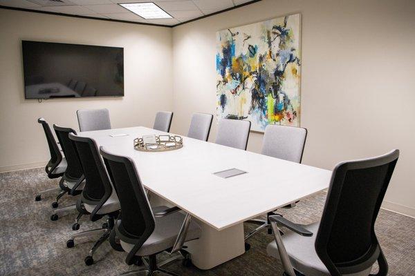 Another spacious conference room with large screen television, table with data ports