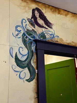 Mermaid mural above door.