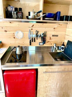 Stove, tea kettle, mini fridge, and sink with mugs