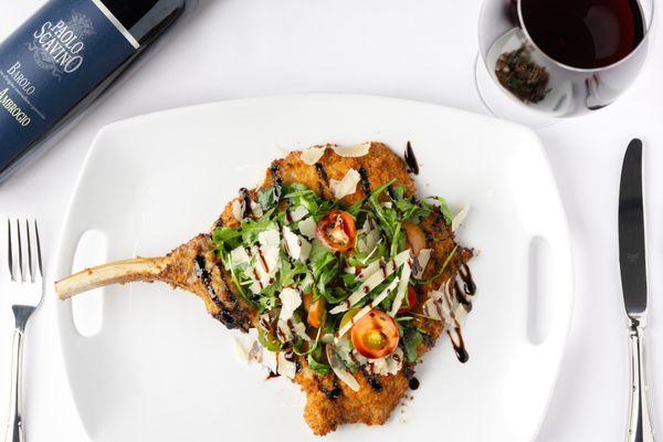 Veal Milanese - Fourteen Ounce Bone-In Veal Chop Pounded Thin & Breaded. Balsamic Glaze, Arugula, Heirloom Cherry Tomato & Parmesan