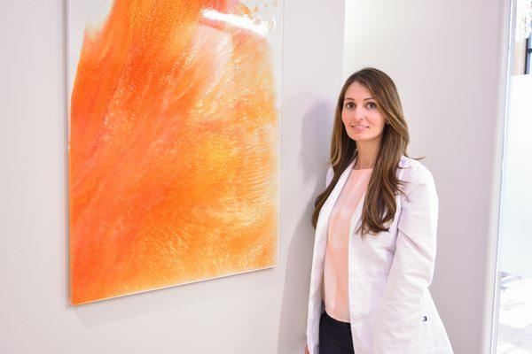 Dr. Karina Bartz next to one of her own paintings in the practice.