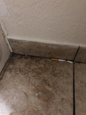 Cigarette left on dirty bathroom floor