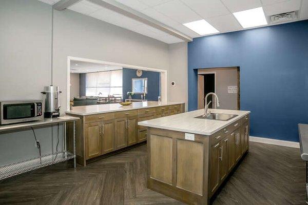 Kitchen with refrigerator, freezer, microwave and coffee percolator.