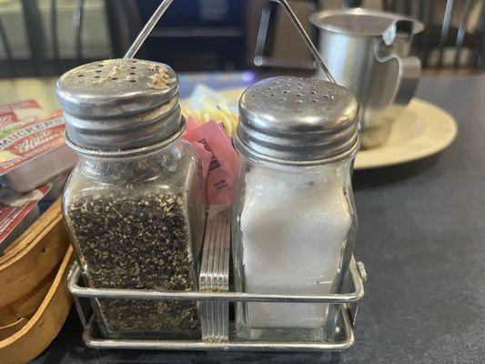 Black things floating around in salt shaker and what seems to be dried gravy caked on the top of the pepper shaker.