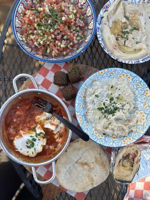 Israeli salad, hummus, falafel, shakshuka, babaganoush, pita and breakfast sandwich