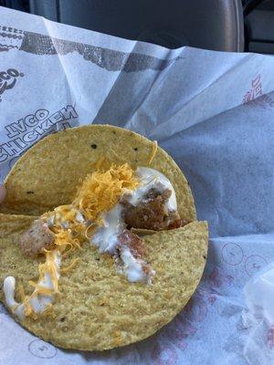 Two pieces of chicken in a taco.