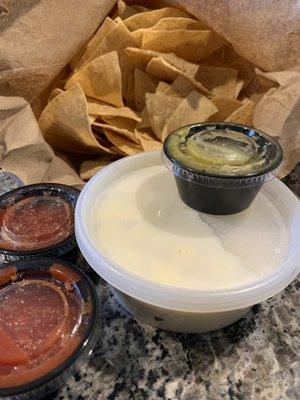 Huge bag of chips, two red salsa, one salsa verde, cheese dip