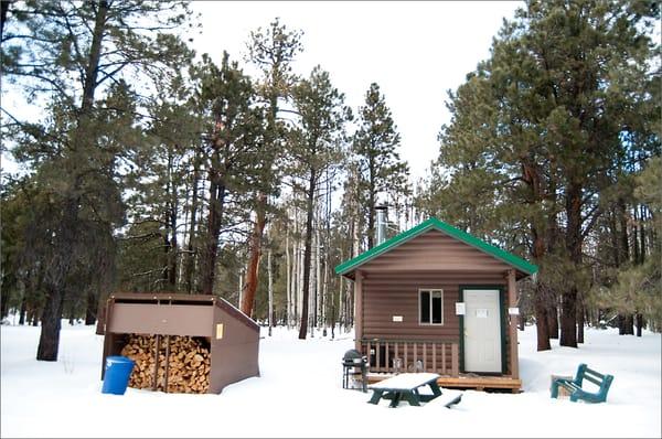 Cabin (Juniper), table, gas grill, wood, trash and recycle bins. Not pictured is the port-o-potty (far left).