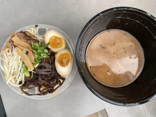 Black garlic tonkatsu as packaged for take-out in two layer compartment bowl.