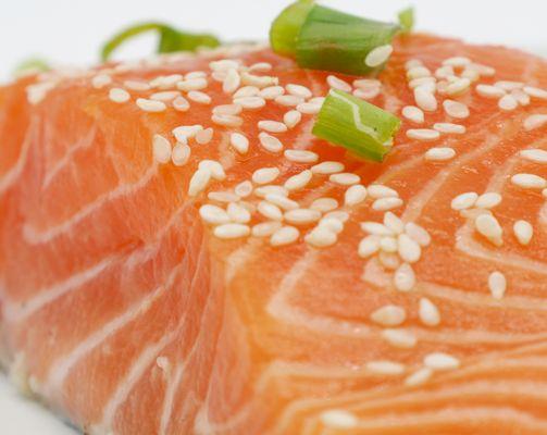 Cut of salmon with sesame seeds and scallions.