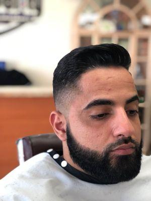 From view of a comb over mid fade with a sharp beard