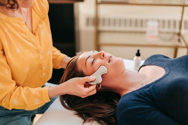 Patient getting gentle gua sha facial massage at Seneca Falls Acupuncture, as part of a cosmetic acupuncture treatment.