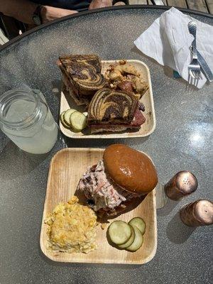 Reuben sandwich with warm potato salad and pulled pork sandwich with corn pudding