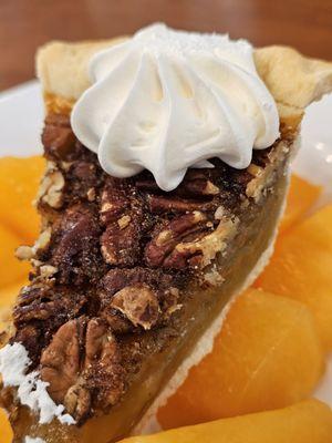 Close-up of a bowl of sweet ripe pieces of cantaloupe with a slide of Pecan Pie on top.