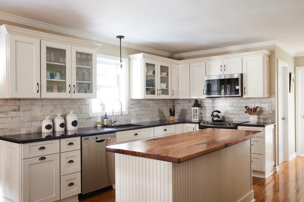 Ivory shaker cabinets with black granite counter tops and rustic backsplash tiles.