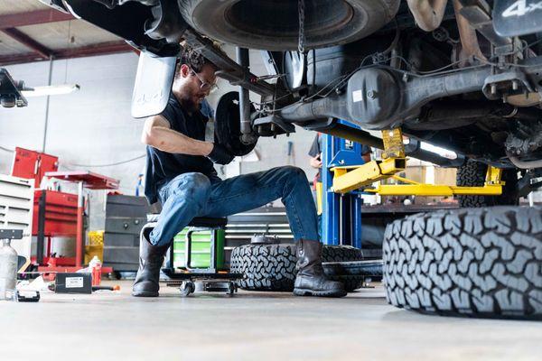 Dedicated mechanic working on a vehicle, showcasing our commitment to thorough and precise auto repairs.