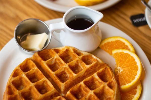 Delicious Belgian Waffle with orange slices, butter and maple syrup