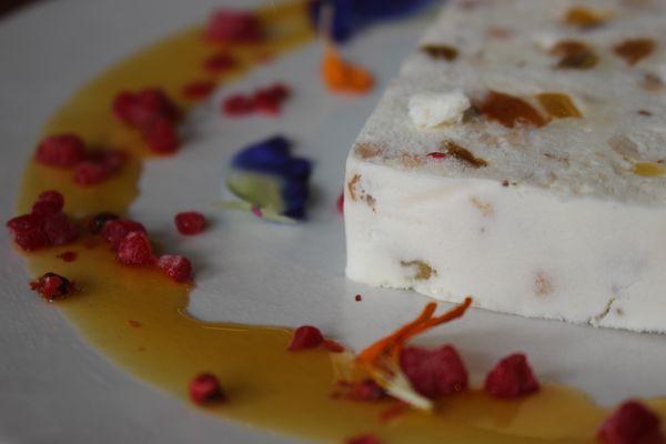 White Chocolate Cassata is italian ice cream cake with walnuts, macadamia nuts, dried fruits, lilikoi sauce, and pink pepper.